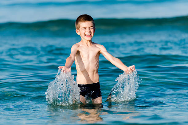 Beautiful boy making splashes in the middle of sea waves stock photo