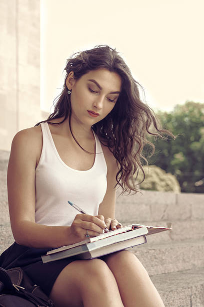 istock Girl with books sitting on the steps 544109554