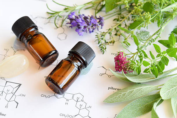 essential oils and science essential oils on the scientific sheet with medicinal  herbs aromatherapy oil photos stock pictures, royalty-free photos & images