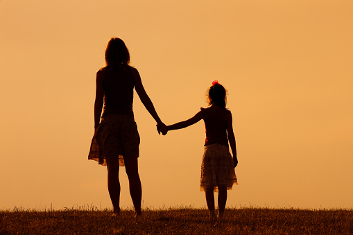 Mother and daughter enjoy watching sunset together.