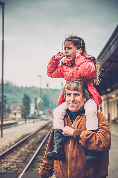 niña tapando las orejas mientras el abuelo el hombro, la estación de ferrocarril - coat grandfather grandchild granddaughter fotografías e imágenes de stock