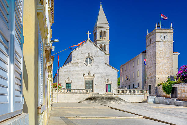 Parish church of Mary’s Annunciation, Supetar. Parish church and clock tower Leroy are marble landmarks in island of Brac, town Supetar, Croatia. Selective focus. old catholic church on island brac croatia stock pictures, royalty-free photos & images