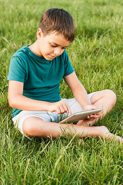 istock Young boy with a tablet on the grass 544125392