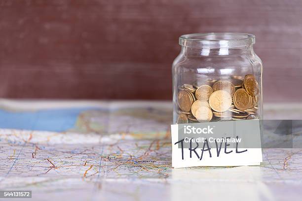 Coins In A Jar With Travel Sign On A Map Stock Photo - Download Image Now - Budget, Home Finances, Travel