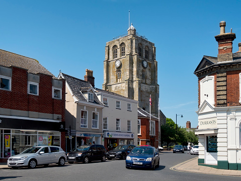 Beccles, Suffolk, England - June 6, 2016: A few people in the town centre of Beccles on a sunny spring day. The bell tower is detached from the main structure of St Michael’s church and is Grade I listed: it was constructed in the early 16th century. Beccles is a traditional English market town in Suffolk, eastern England.