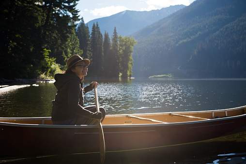 Female paddling a canoe on a pristine mountain lake at surise