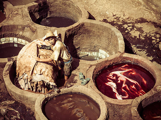 Workers and dyeing in red hides in the vats of Fez tanneries, Morocco.
