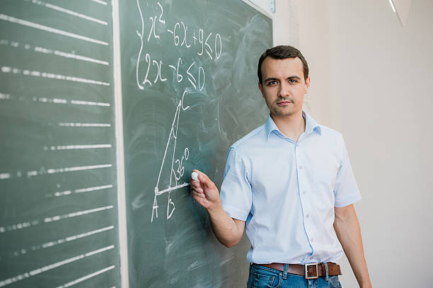 istock Young male teacher or student holding chalk writing on chalkboard 544140526
