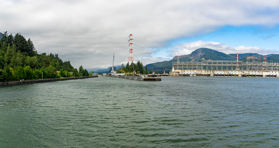 Bonneville Dam with Oregon on the left side, then the Navigation Lock and the First Powerhouse on the right side. Picture taken from the Columbia River. This dam is located in the Columbia River, the division between the State of Oregon and Washington. Photo merged images.