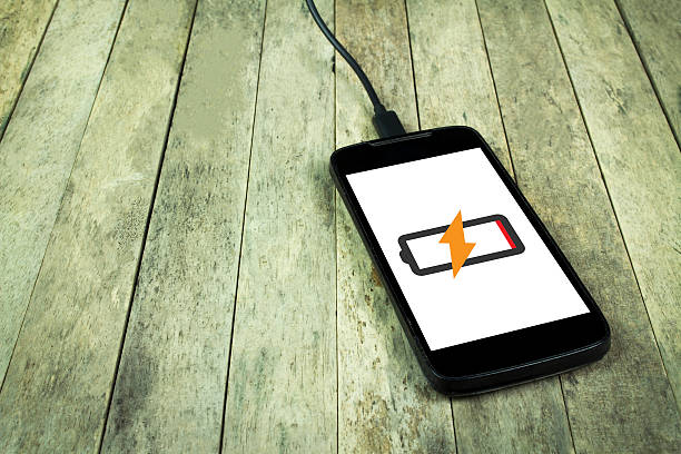 istock Smart phone is charging on wood background, copy space 544311596