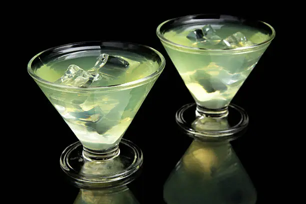 Close-up view of margarita drinks with ice cubes on a party on black background