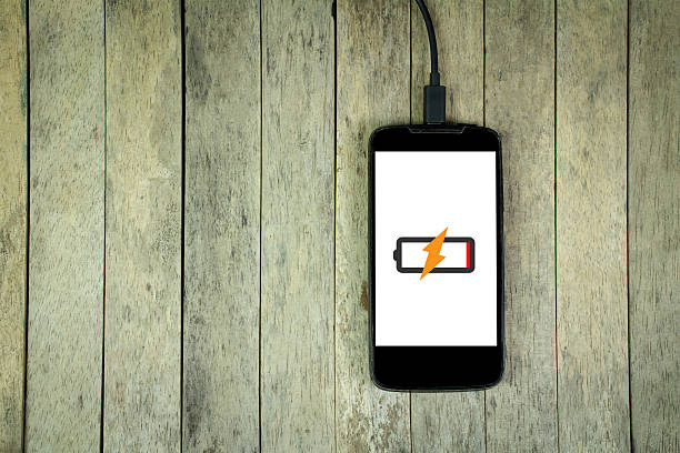 istock Smart phone is charging on wood background, copy space 544319314