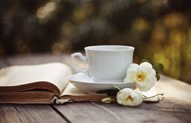 istock Cup with a flowers of rose on an open book 544320476