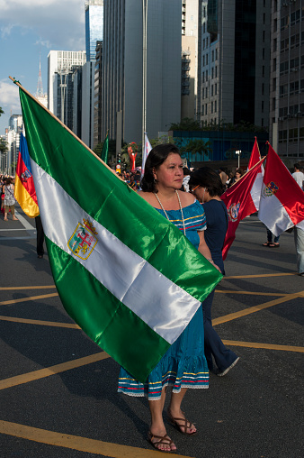 São Paulo, Brazil - July 03, 2016: Woman carries the flag of the Department of Santa Cruz from Bolivia at a parade on Paulista Avenue to commemorate the day of the immigrant. In recent years many Bolivian immigrants is coming to São Paulo to work in the textile industryWoman carries the flag of the Department of Santa Cruz of Bolivia at a parade on