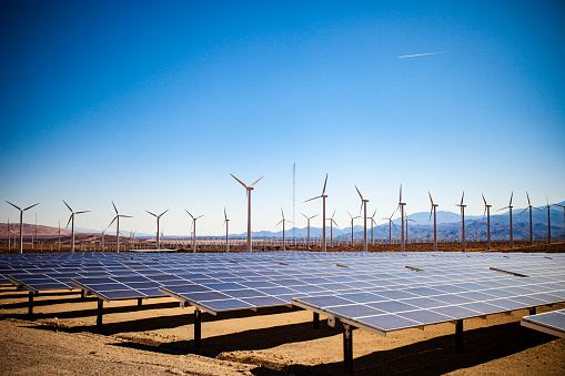 Image of a field of solar panels and windmills in the desert.