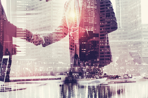 Businessmen shaking hands. This is a montage which has a city scape overlaid. Success concept