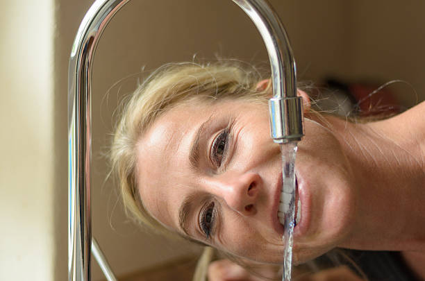 istock Smiling woman drinking from a kitchen faucet 544332172