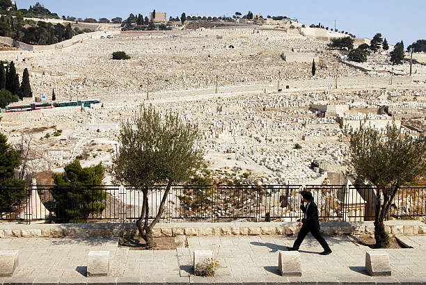 Jerusalem, Israel - September 28, 2007: Jewish man passes by Mount of Olives in Jerusalem , Israel. The Jewish cemetery on Mt olives is over 3, 000 years and holds approximately 150,000 graves.