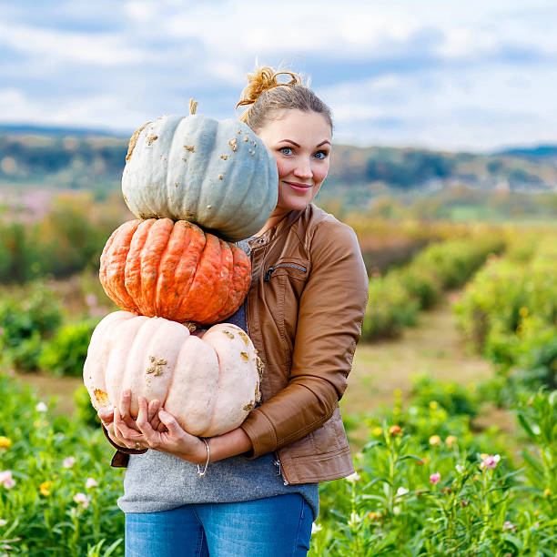 istock Beautiful woman with three huge pumpkins on farm 544340116