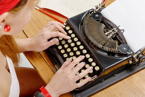 closeup of hands of a young woman with an old typewriter
