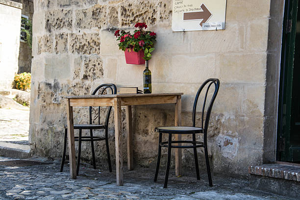 Two chairs, table, book and bottle of wine in streets of Matera. Real atmosphere of this ancient city in Italy captured in one photo. 