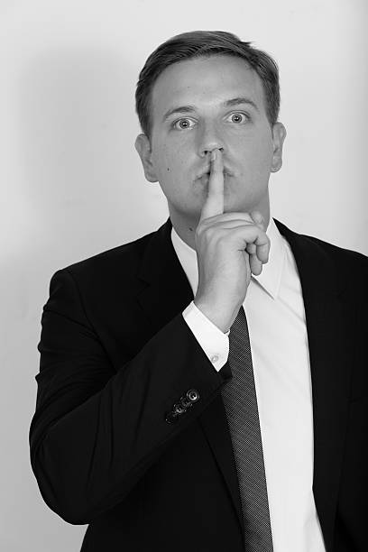retrato preto e branco de empresário segurando dedo nos lábios - finger on lips black and white secrecy men - fotografias e filmes do acervo