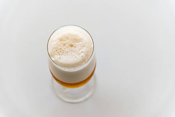 Glass of fresh lager beer on white table