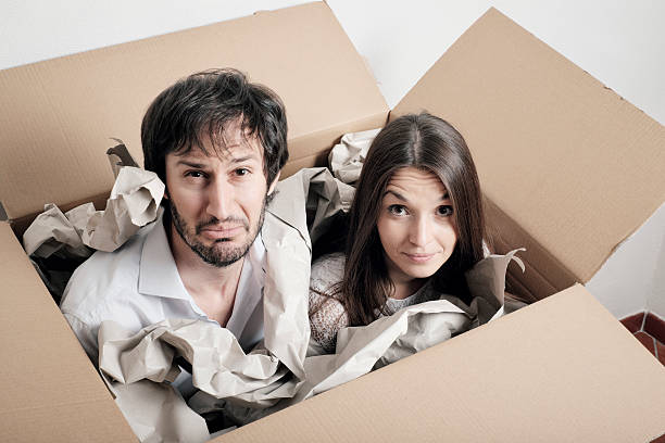 istock Shipping people in a box - puzzled young couple 544350174