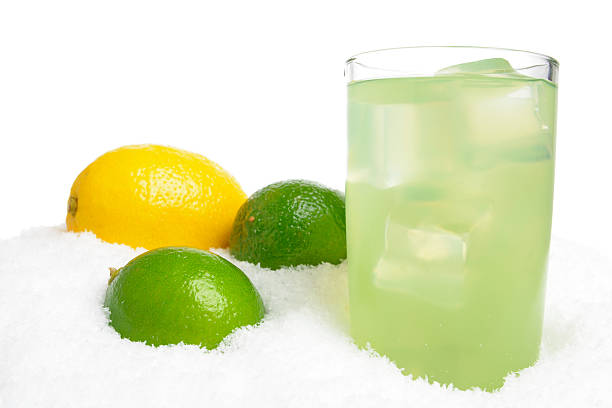 Glass of lime juice with ice cubes,limes,lemon on snow on white background