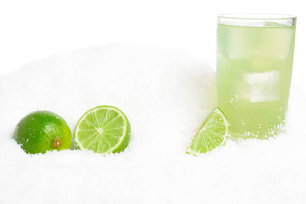 Glass of lime juice with ice cubes,limes on snow on white background