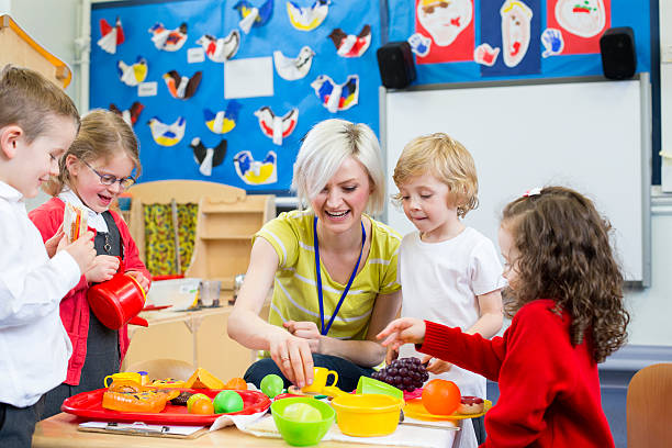 Roleplay Restaurant at Nursery Nursery teacher playing kitchen roleplay with her students in the classroom. preschool classroom jobs stock pictures, royalty-free photos & images