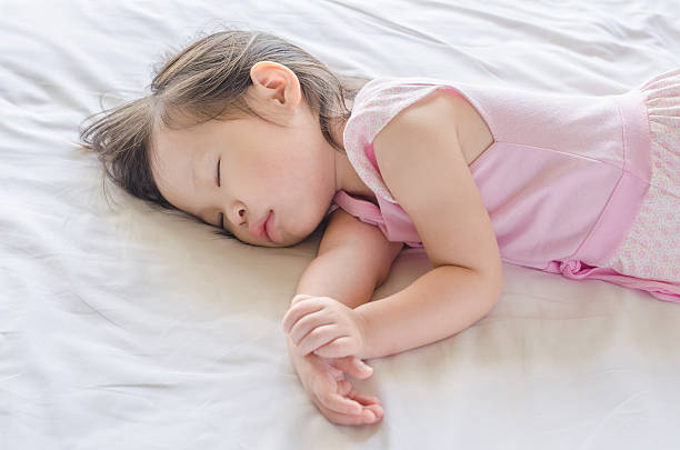 Little girl sleeping on bed stock photo