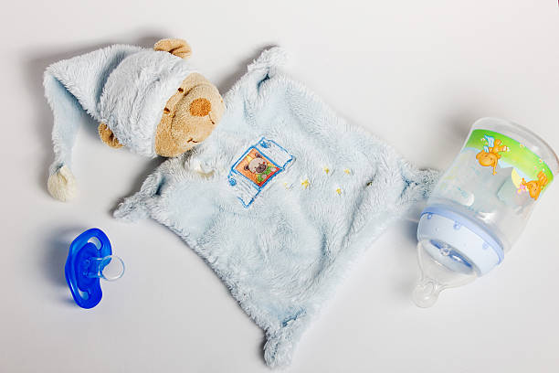 Baby boy in onesie with pacifier in his mouth playing and trying to stand up in the crib