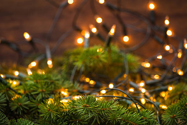 istock Fir-tree branch with christmas lights over the wooden surface 544442882