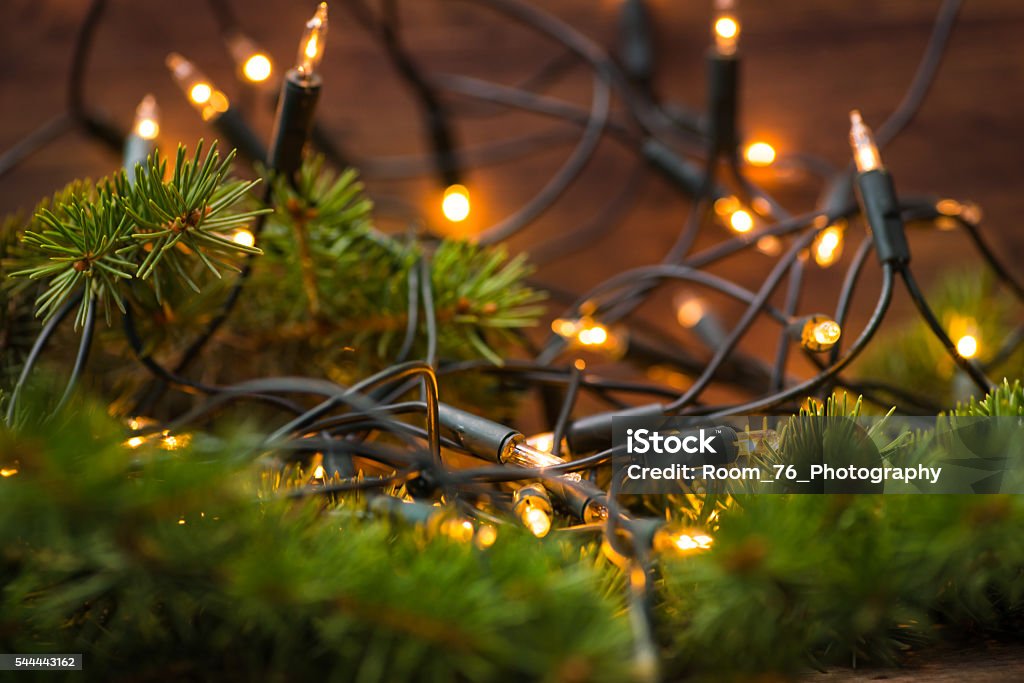 Fir-tree branch with christmas lights over the wooden surface Fir-tree branch with christmas lights on a wooden surface Backgrounds Stock Photo