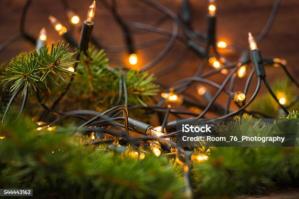 Firtree Branch With Christmas Lights Over The Wooden Surface Stock Photo - Download Image Now