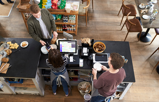 High angle view of man paying over counter at a coffee shop