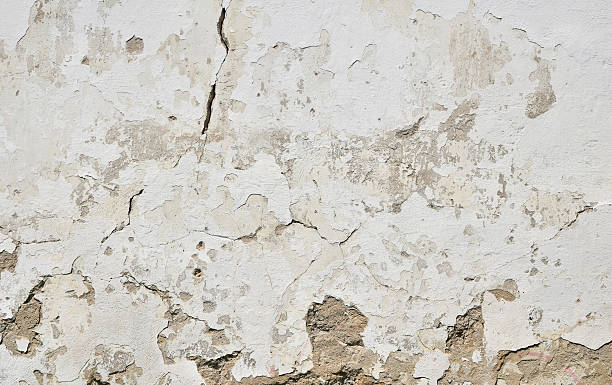 istock Old white painted plaster wall with cracks and stains 544446674