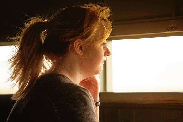 istock young woman looking through window in bird hide 544449360
