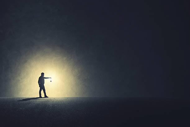 hombre con lámpara caminando iluminando su camino - una sola vía fotografías e imágenes de stock