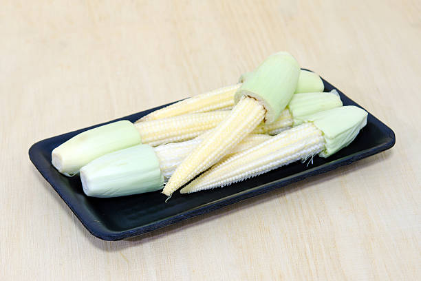 istock Baby corn fruit grouped on black plate on wooden board 544453182
