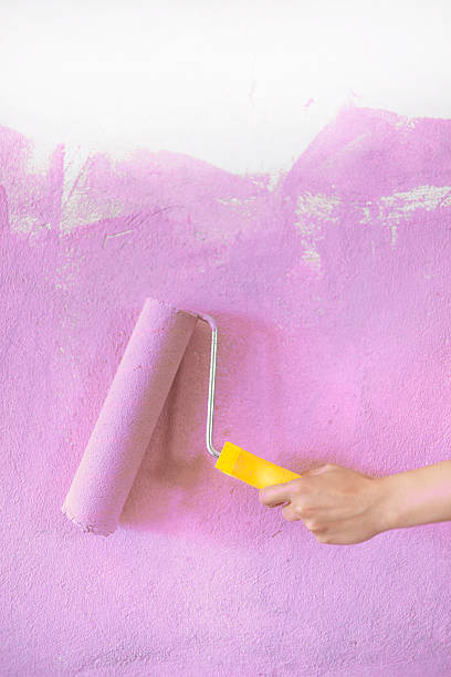 istock Female hand holding a roller with pink paint 544459518
