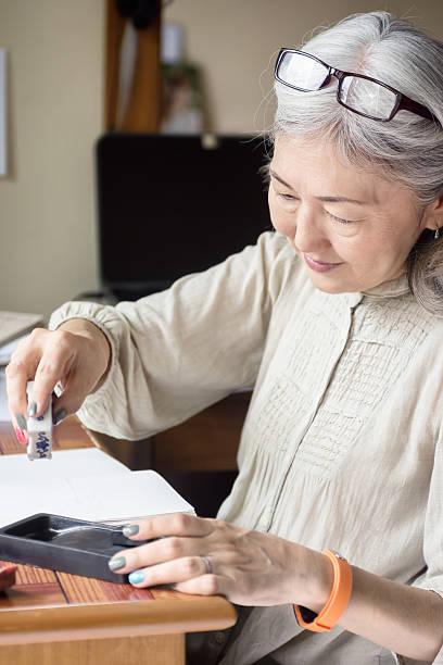 Asian senior woman artist using Suiteki and sudzuri stock photo