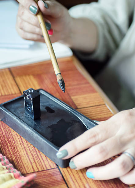 artist hand holding fude brush for sumi-e painting over suzuri - inkstone imagens e fotografias de stock