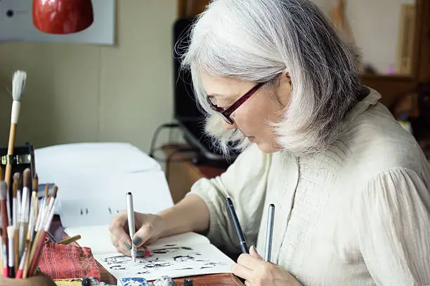 Photo of Asian senior woman artist sketching