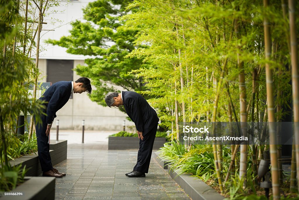 Traditional Japanese business greeting Japanese businessmen bowing in traditional Japanese customs used when greeting colleagues and formalizing deals Social Grace Stock Photo