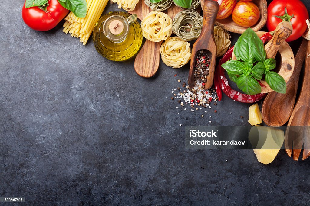 Italian food cooking Italian food cooking. Tomatoes, basil, spaghetti pasta, olive oil and chili pepper on stone kitchen table. Top view with copy space for your recipe Italian Food Stock Photo