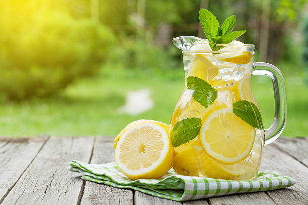 Lemonade with lemon, mint and ice Lemonade pitcher with lemon, mint and ice on garden table. View with copy space pitcher jug stock pictures, royalty-free photos & images