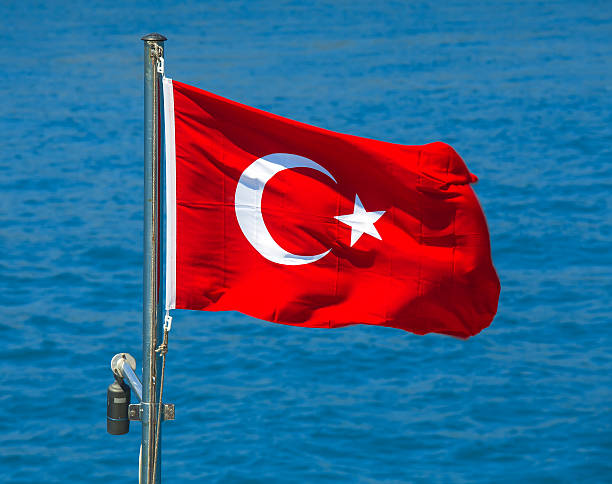 istock Turkish flag in sun rays on the sea water background. 544469212