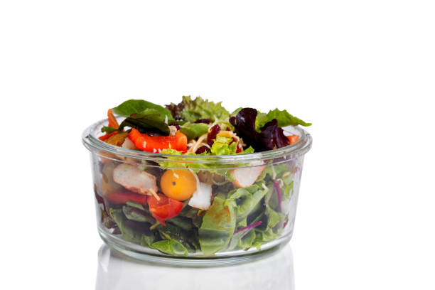 Fresh mixed salad in glass container isolated on white with reflection
